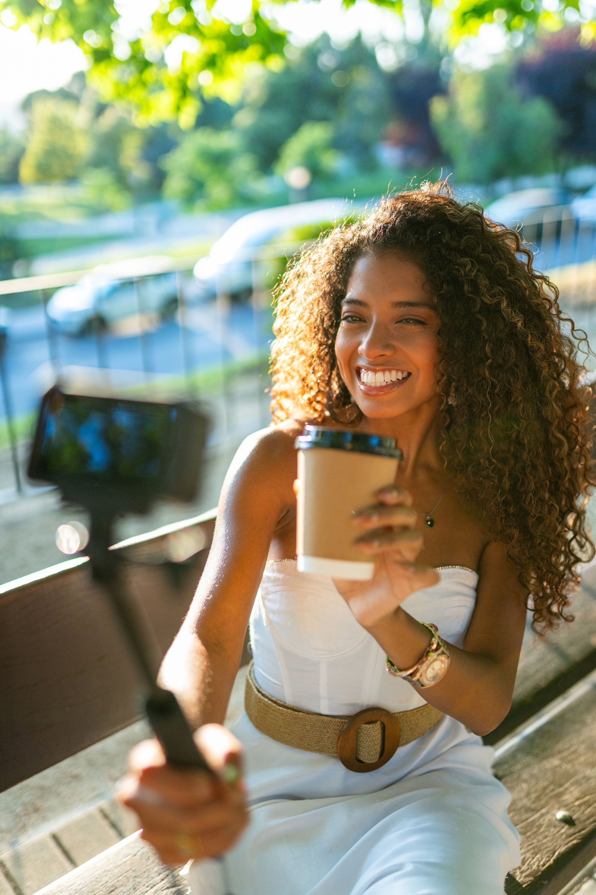 Young woman vlogging about coffee while sitting on a bench