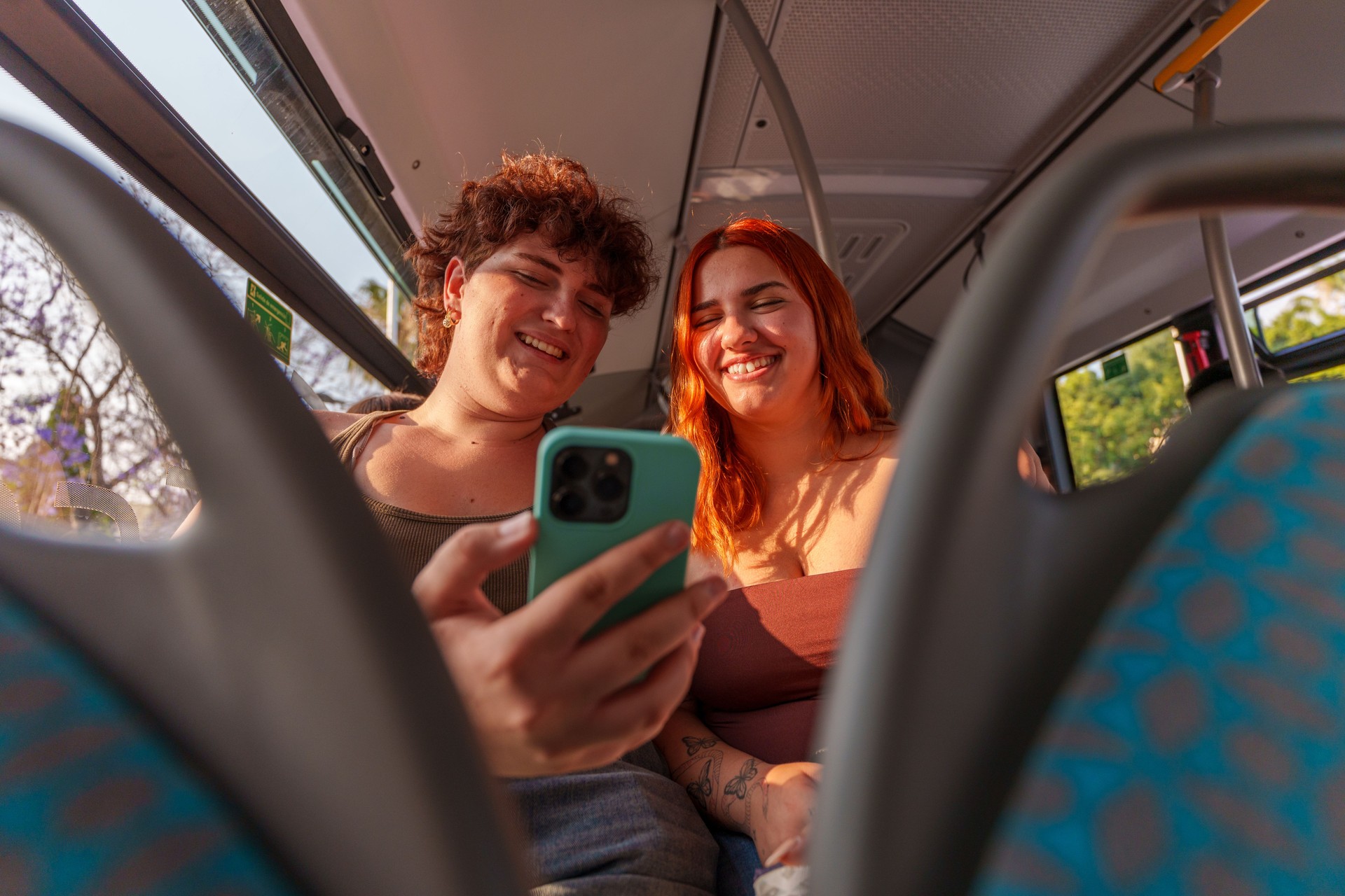Two young women looking at smartphone on the bus during their trip